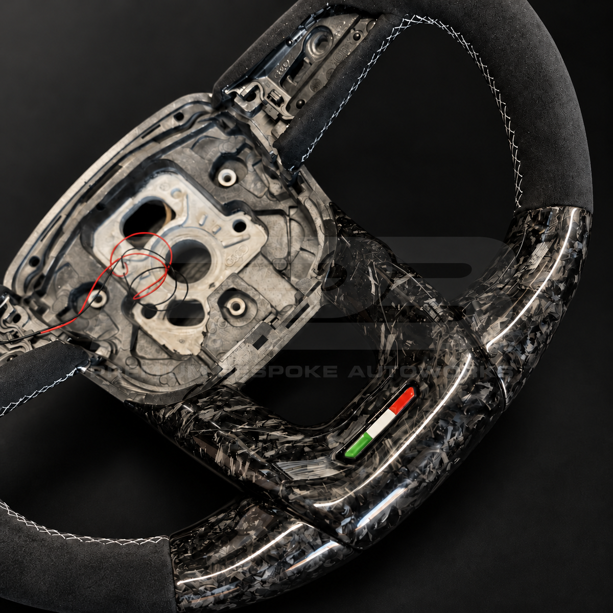 Lamborghini Urus custom steering wheel, close view of the gloss forged carbon lower trim with Italian flag badge and silver stitched Alcantara grip