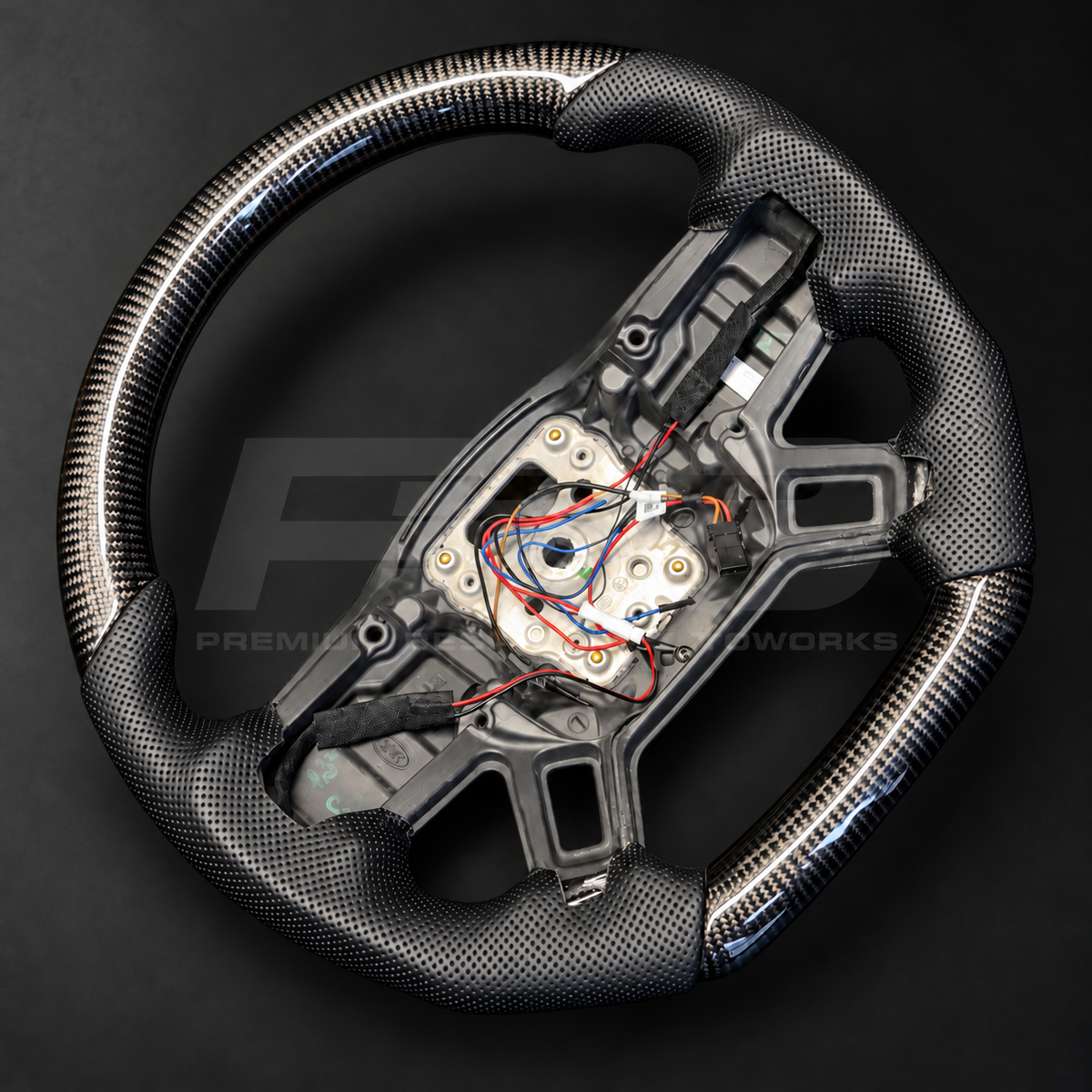 Land Rover Defender L663 custom steering wheel, side angle showing the carbon fibre top and bottom with perforated leather grips