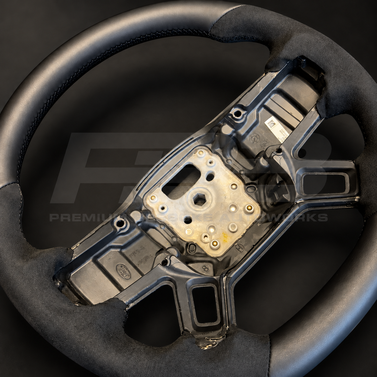 Close up of Land Rover Defender L663 custom steering wheel black stitching where smooth leather meets Alcantara
