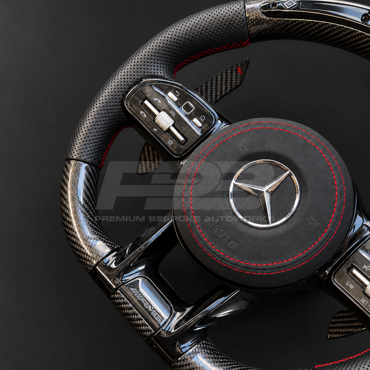Mercedes-AMG C43 W205 Facelift custom steering wheel close up detail showing gloss carbon fibre top and bottom, RPM lights bar, black perforated leather grips, red stitching and Alcantara airbag cover