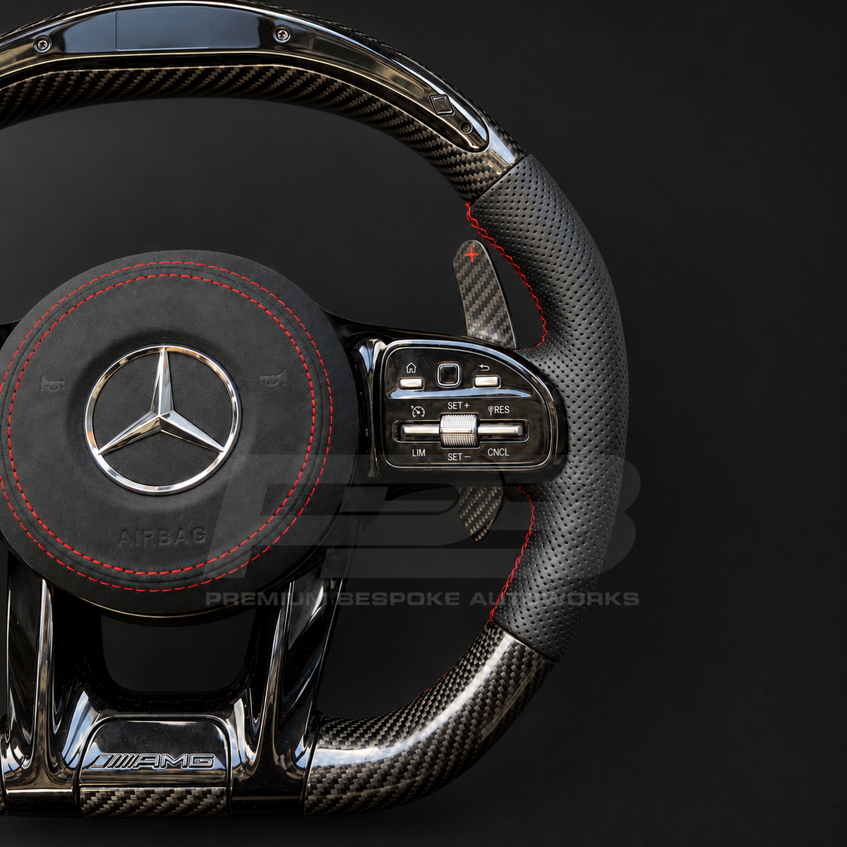 Mercedes-AMG C43 W205 Facelift custom steering wheel close up detail showing gloss carbon fibre top and bottom, RPM lights bar, black perforated leather grips, red stitching and Alcantara airbag cover