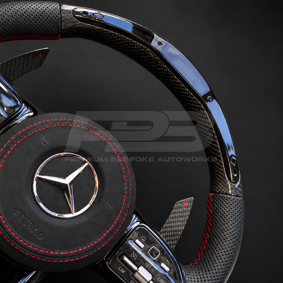 Mercedes-AMG C43 W205 Facelift custom steering wheel close up detail showing gloss carbon fibre top and bottom, RPM lights bar, black perforated leather grips, red stitching and Alcantara airbag cover