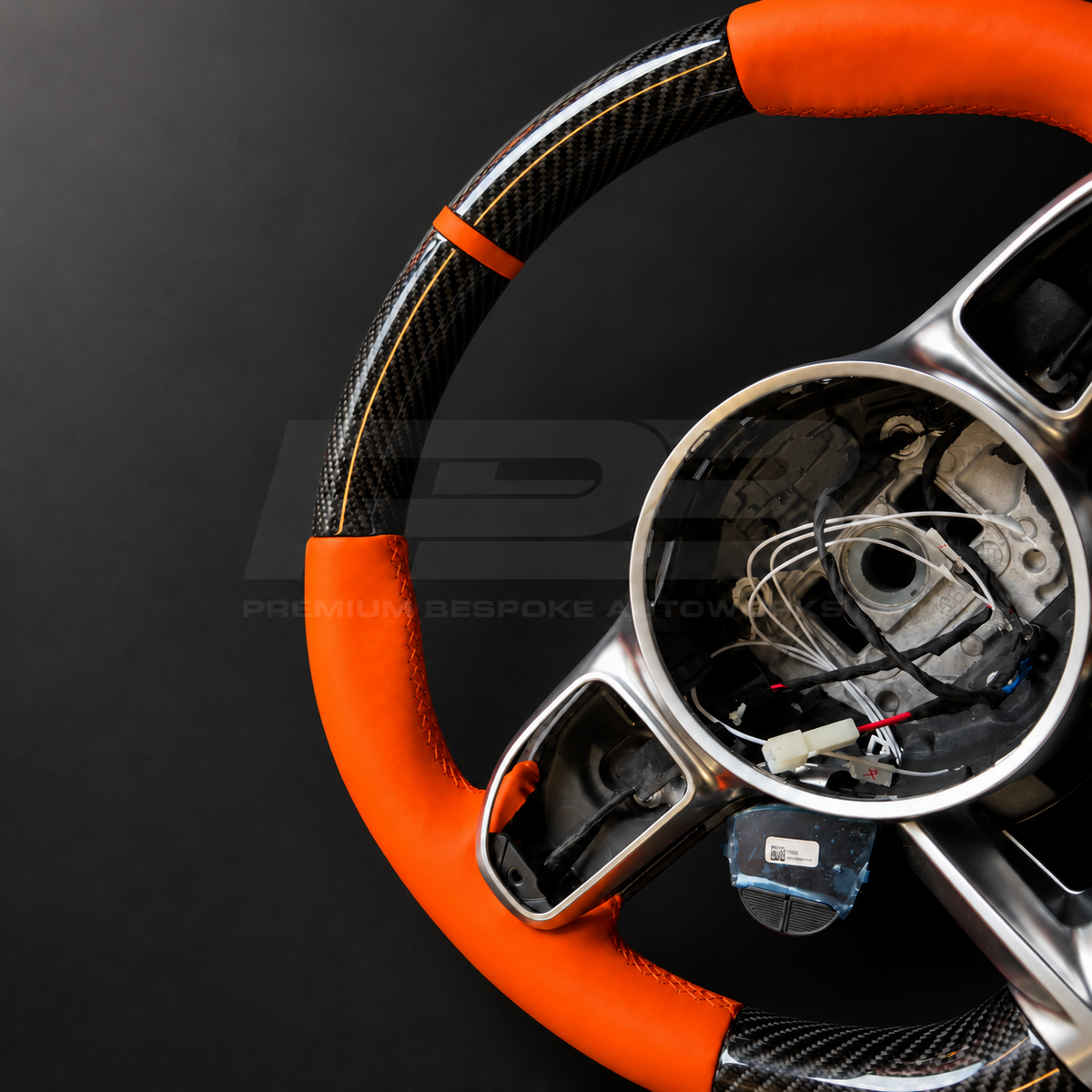 Mercedes-AMG G63 W463 Facelift custom steering wheel close up detail showing gloss carbon fibre top and bottom, orange leather grips and orange 12 o'clock marker