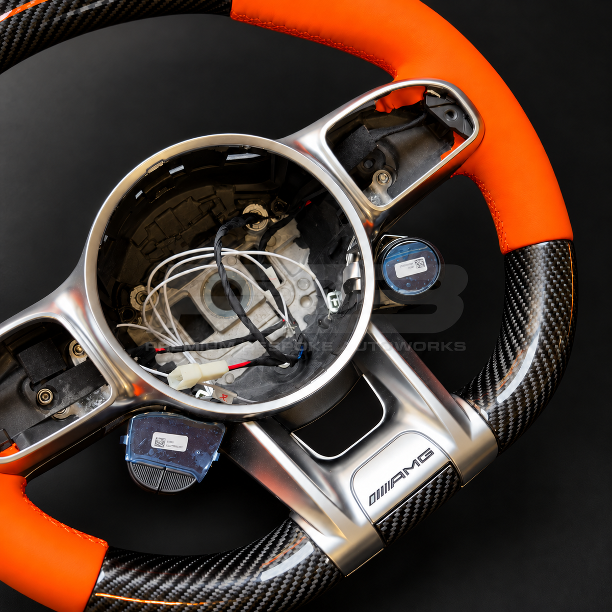 Mercedes-AMG G63 W463 Facelift custom steering wheel close up detail showing gloss carbon fibre top and bottom, orange leather grips and orange 12 o'clock marker