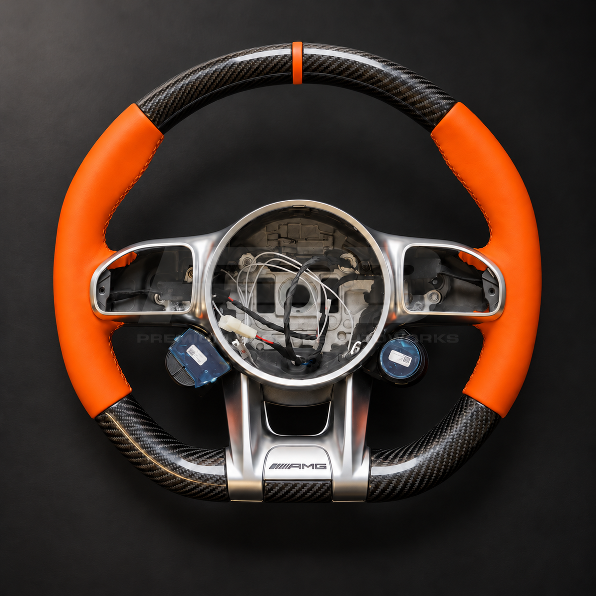 Mercedes-AMG G63 W463 Facelift custom steering wheel front view showing gloss carbon fibre top and bottom, orange leather grips and orange 12 o'clock marker