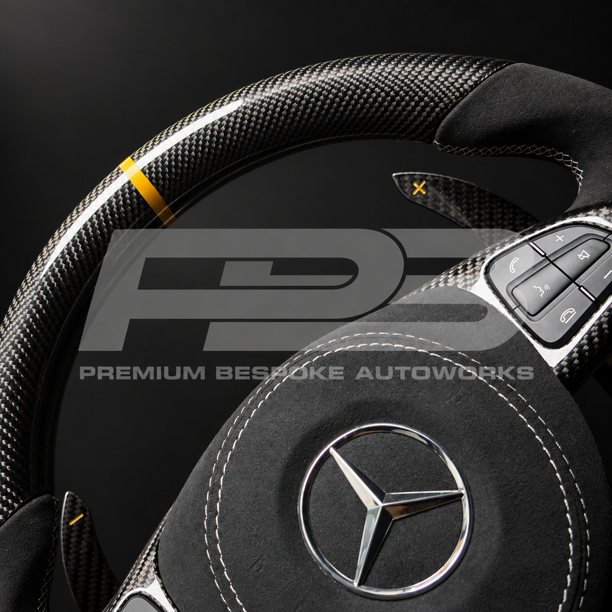 Close up of the gloss carbon fibre top section, gold 12 o'clock marker, Alcantara grip and grey stitched Alcantara airbag cover on a custom Mercedes-AMG GLE 63 steering wheel