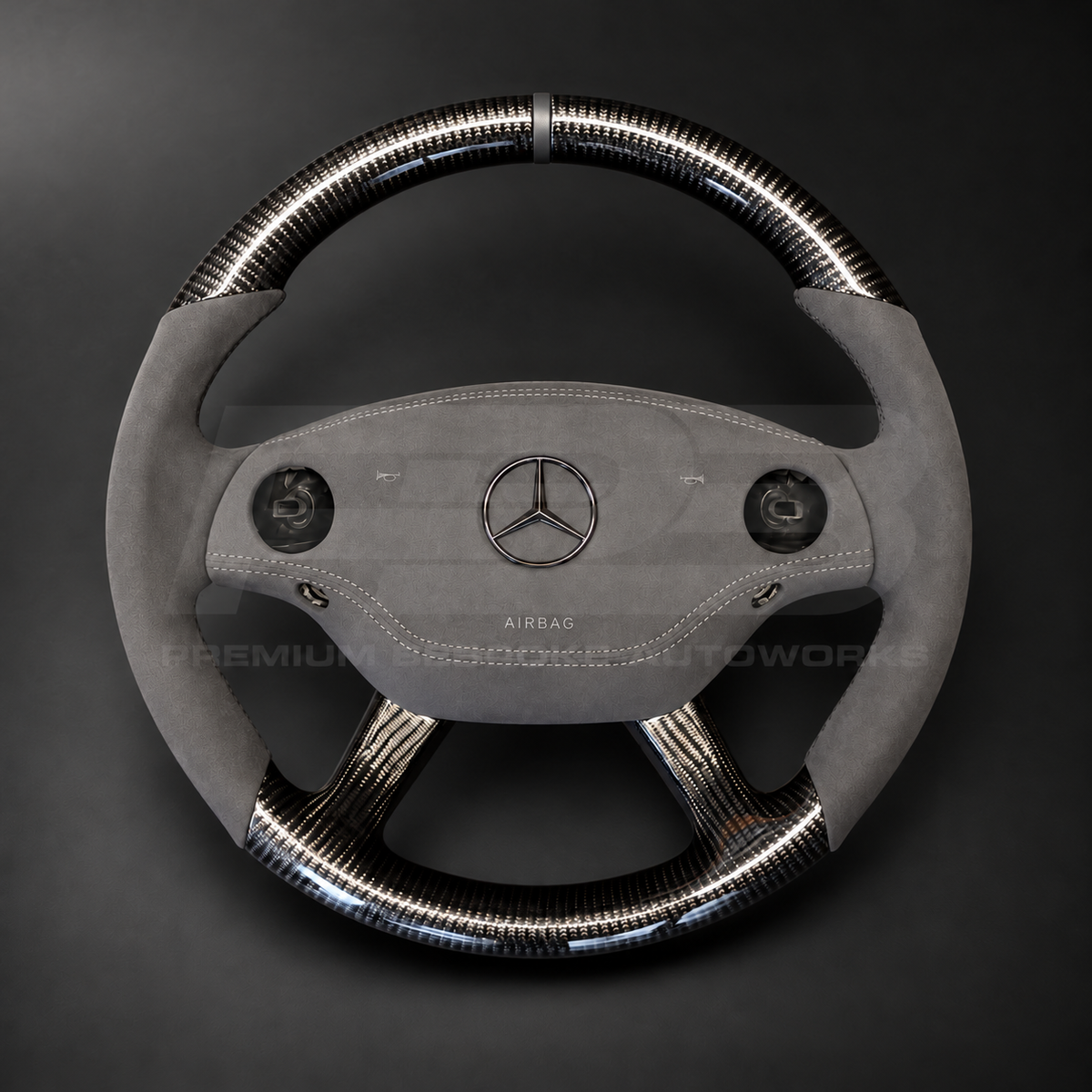 Mercedes CL63 AMG C216 custom steering wheel front view showing round shape, gloss carbon fibre top, bottom and spokes, dark grey Alcantara grips and airbag cover