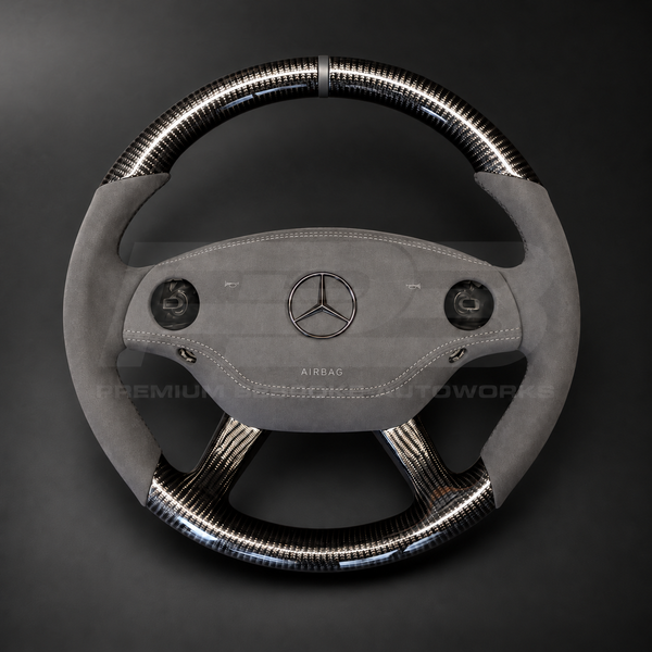 Mercedes CL63 AMG C216 custom steering wheel front view showing round shape, gloss carbon fibre top, bottom and spokes, dark grey Alcantara grips and airbag cover