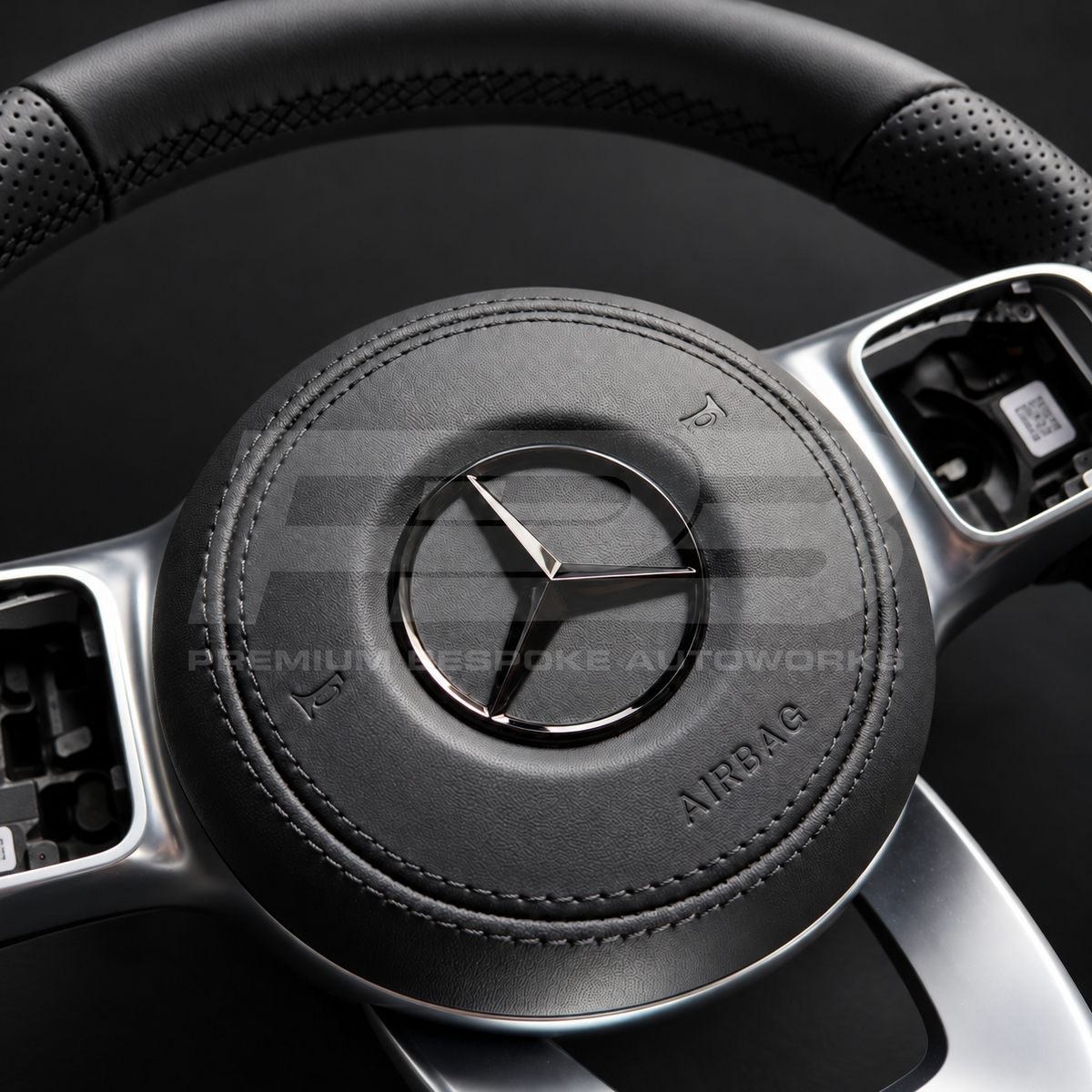 Mercedes-Benz CLS C257 custom steering wheel close up detail showing flat bottom, smooth black leather, perforated grips, black stitching, leather airbag cover, factory silver spokes