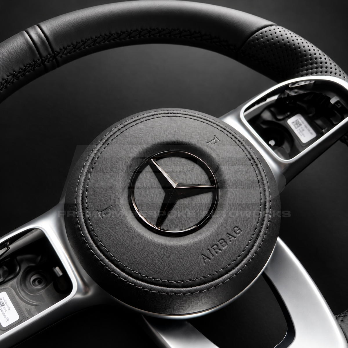 Mercedes-Benz CLS C257 custom steering wheel right angle showing flat bottom, smooth black leather, perforated grips, black stitching, leather airbag cover, factory silver spokes