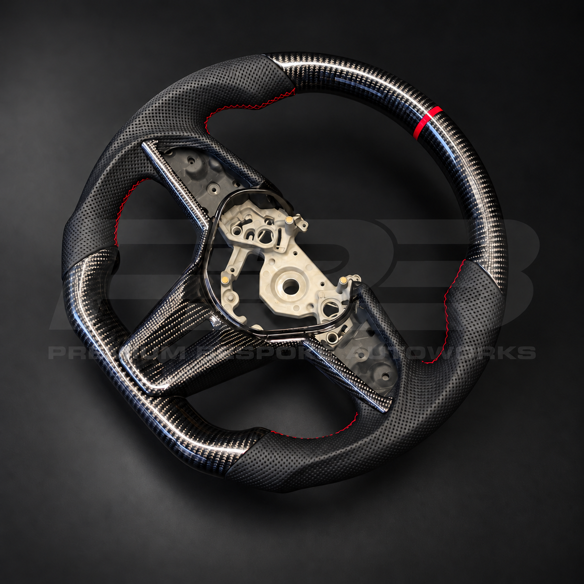 Nissan GT-R R35 EBA custom steering wheel rotated to show the perforated black leather grips with red stitching and gloss carbon fibre spoke trims
