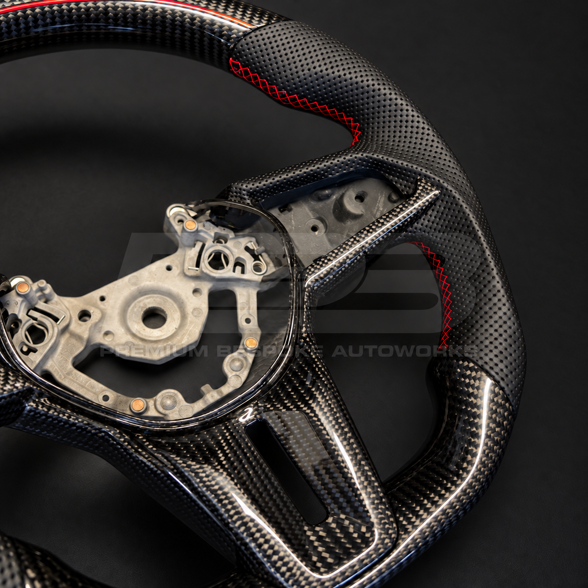 Nissan GT-R R35 EBA custom steering wheel, close angled view of the gloss carbon fibre spoke and lower centre trims and the carbon bottom section