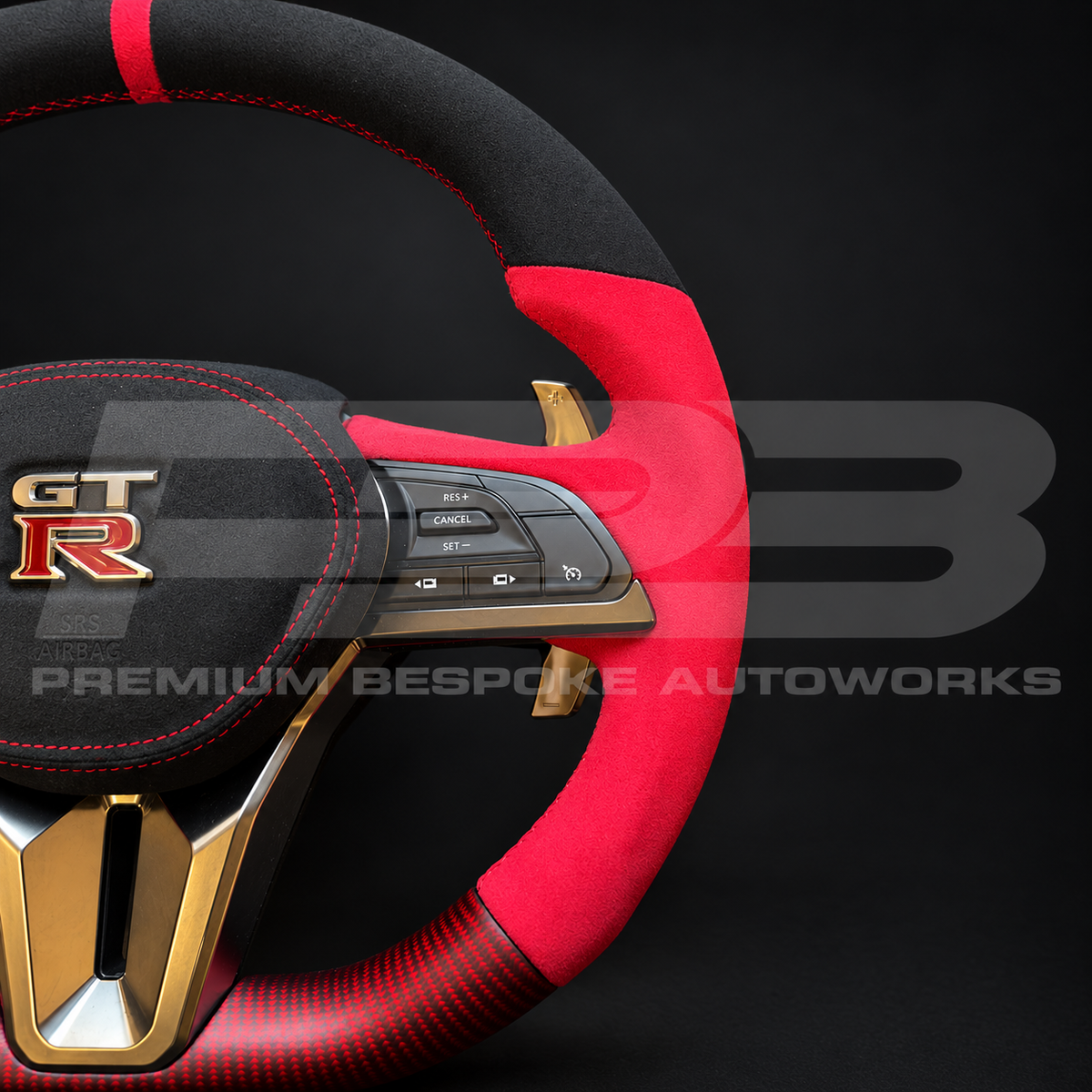Nissan GT-R R35 EBA custom steering wheel detail, red Alcantara grips, red stitching and red carbon fibre lower section with OEM silver trim