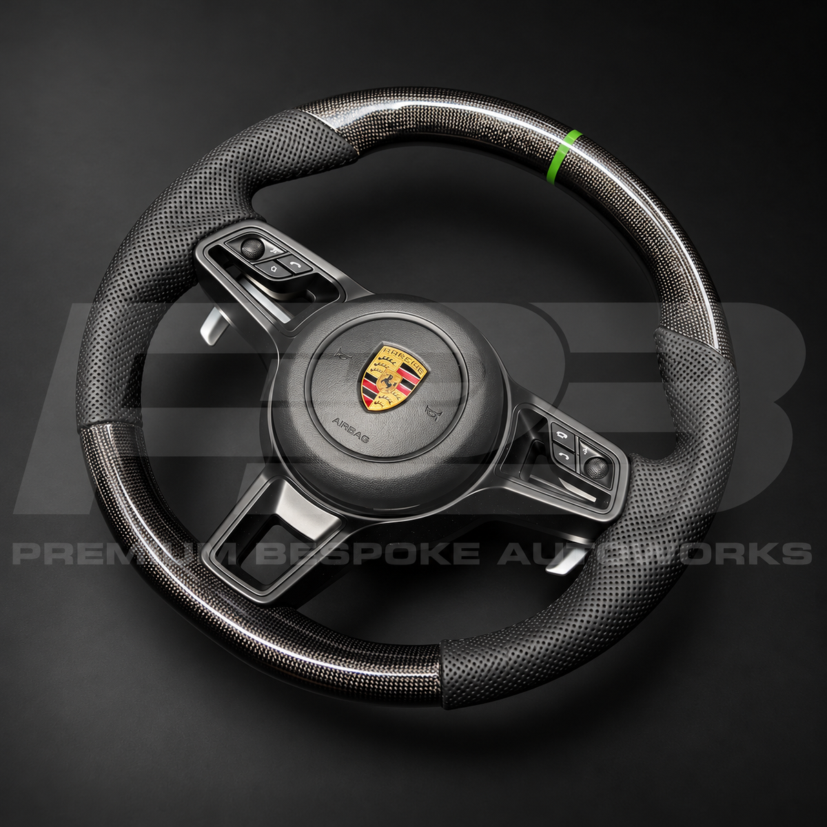 Porsche 911 991.2 custom steering wheel angled from the left, showing the gloss carbon fibre top section, green marker and gloss black paddle shifter