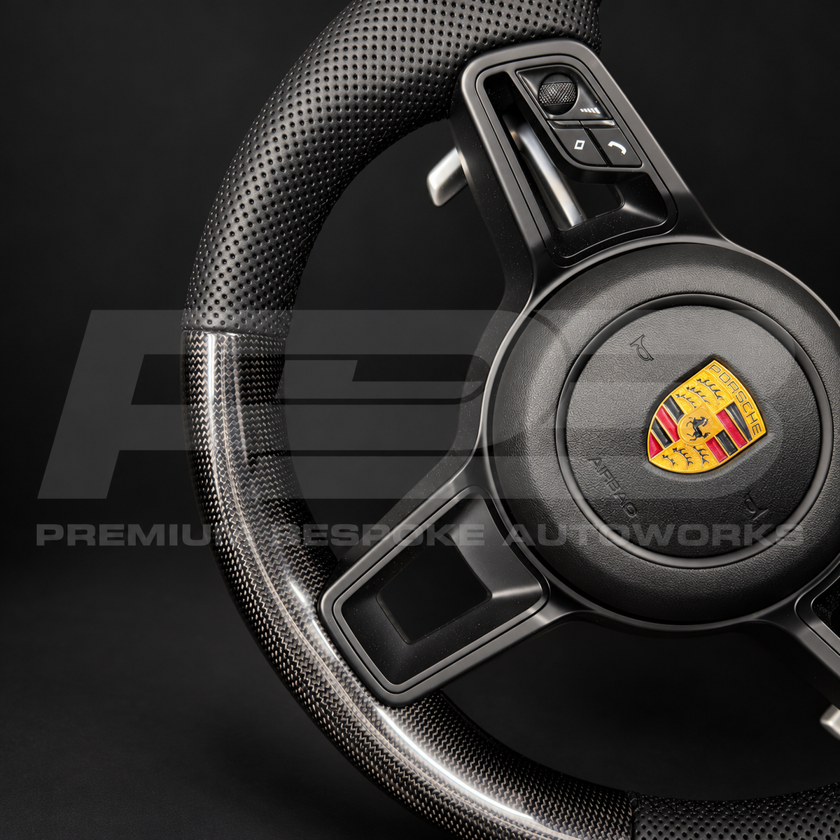 Close up of the perforated black leather grip, gloss black spoke trim, buttons and paddle shifter on a Porsche 911 991.2 custom steering wheel