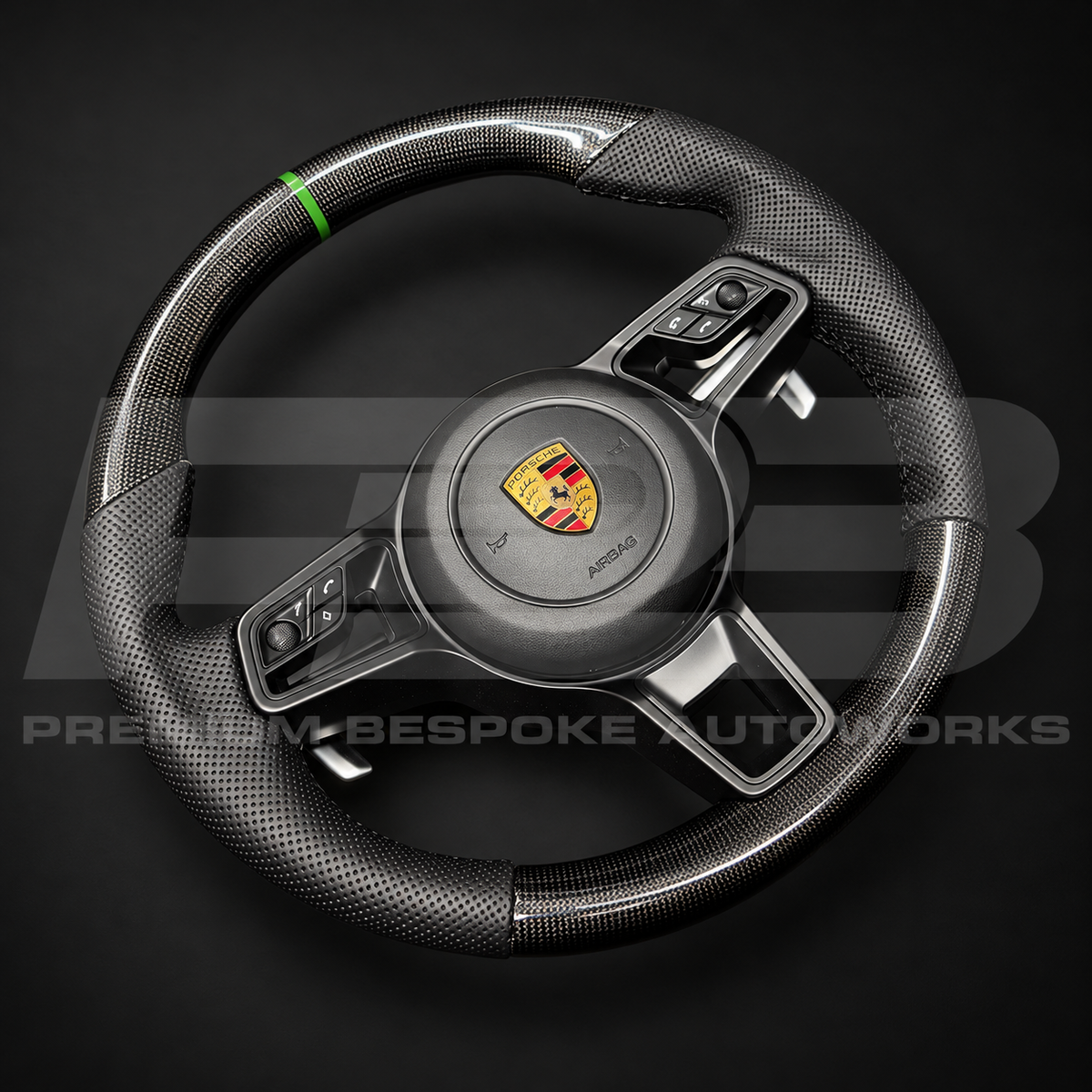 Porsche 911 991.2 custom steering wheel angled from the right, showing the gloss carbon fibre bottom section, perforated leather grips and gloss black trims