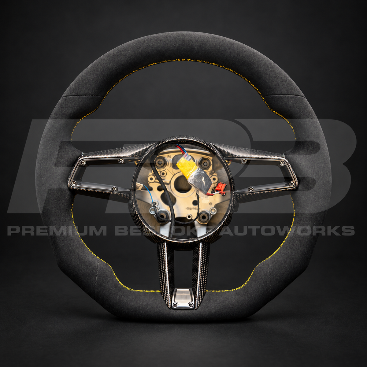 Porsche 911 992 custom steering wheel, front view: flat bottom, black Alcantara top, bottom and grips, yellow stitching, gloss carbon fibre spoke trims