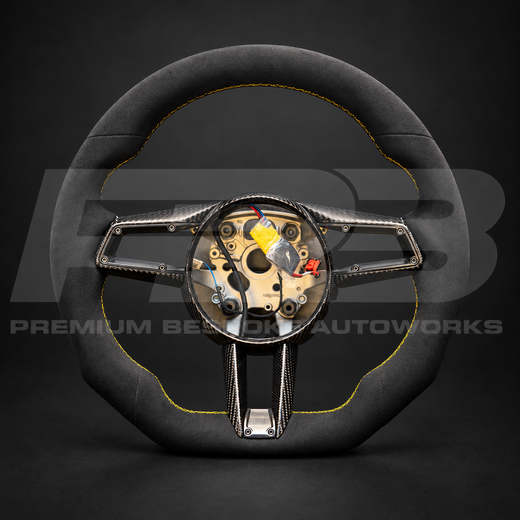 Porsche 911 992 custom steering wheel, front view: flat bottom, black Alcantara top, bottom and grips, yellow stitching, gloss carbon fibre spoke trims