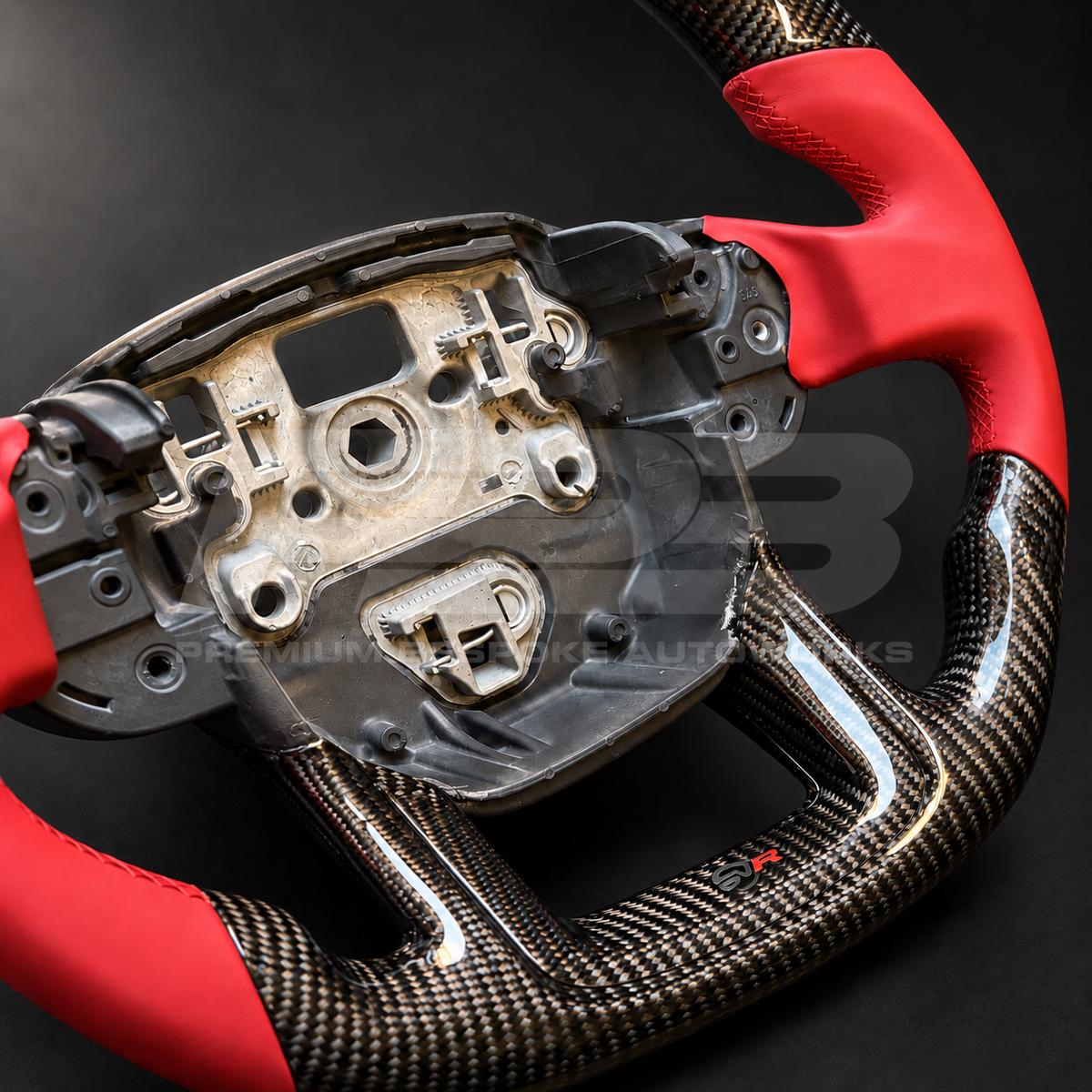 Range Rover Sport L494 SVR custom steering wheel close up detail showing flat bottom, gloss carbon fibre top and bottom, SVR red leather grips and stitching, carbon lower trim with SVR badge